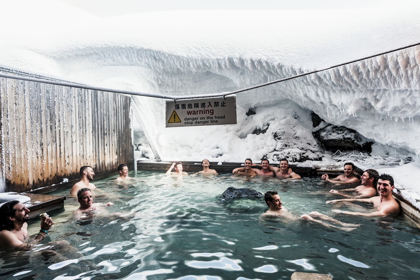 A group of men in the male onsen drinking beer and surrounded by snow at Goshiki onsen in Niseko.