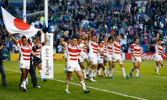 The Japanese rugby union team on the field and holding the flag as they play in the 2015 World Cup in England.